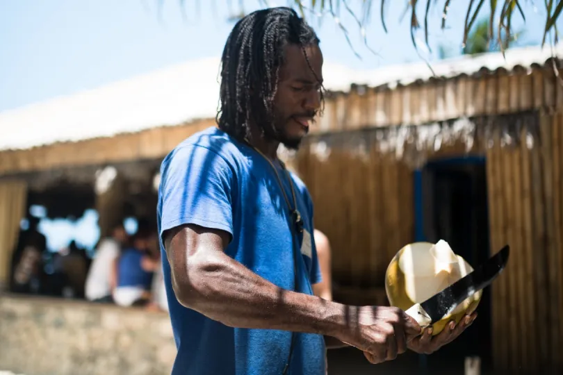 Ein Jamaikaner schneidet eine Kokosnuss am Strand