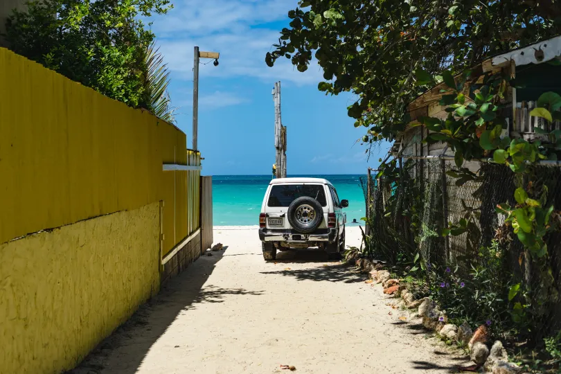 Ein weißes Auto steht am Strand von Jamaika