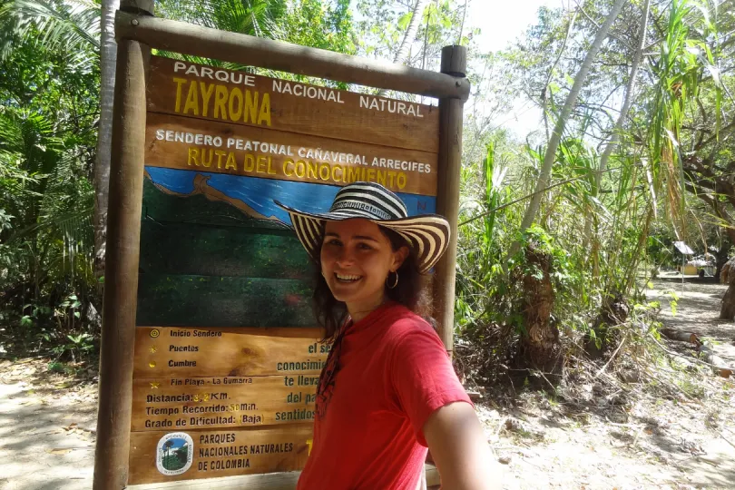 Ein Mädchen steht vor dem Wanderschild im Tayrona Nationalpark