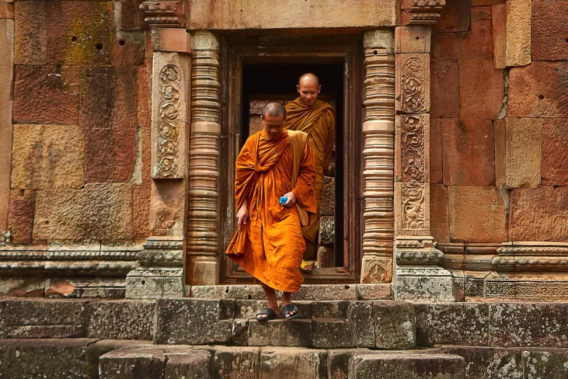 Zwei Mönche in Orange verlassen einen Tempel