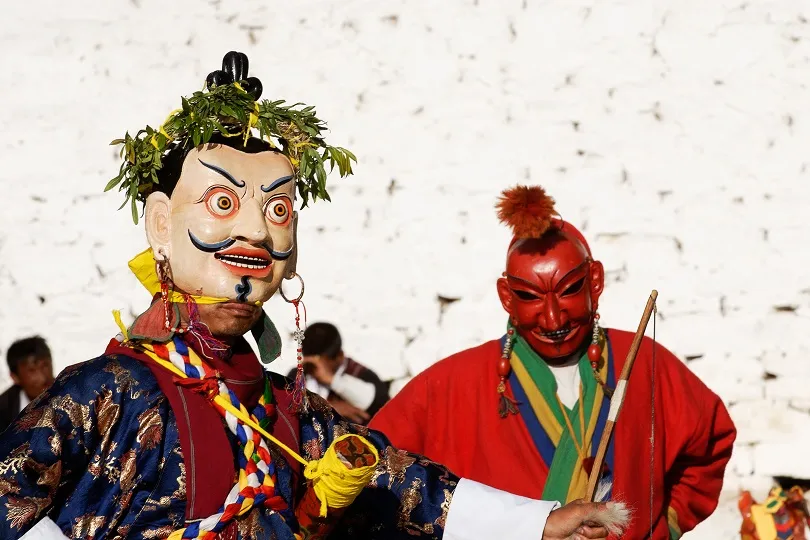 Männer tragen traditionelle Masken bei Festival in Bhutan