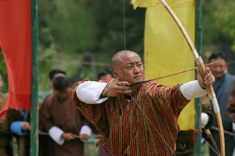Bhutanischer Mann zielt mit Pfeil und Bogen