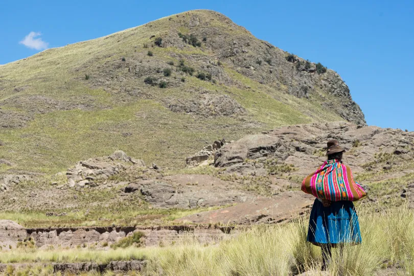 Eine Peruanerin läuft einen Berg in Peru hoch