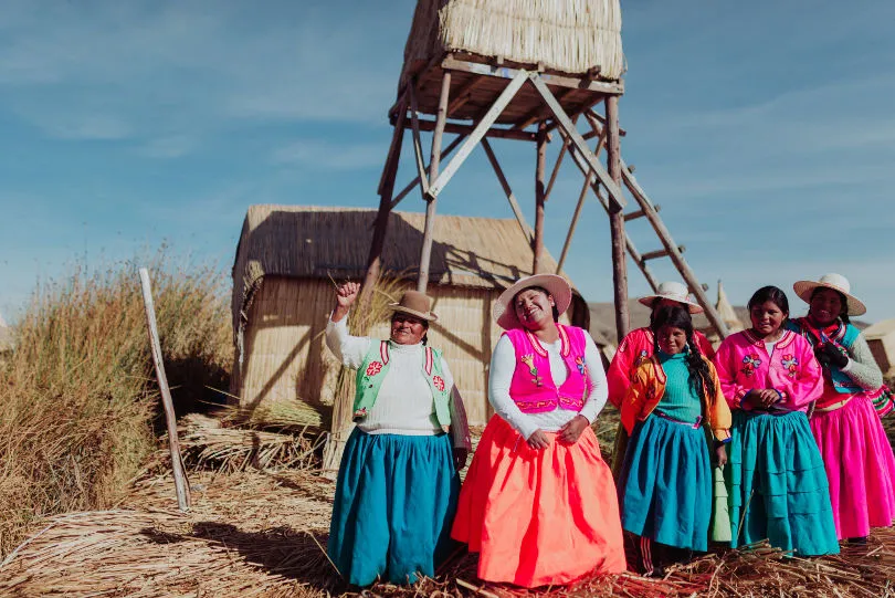Sechs Frauen stehen auf einer Schilfinsel des Titicacsees in Peru und lachen