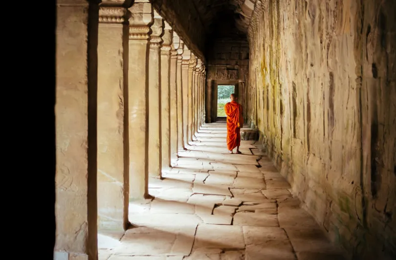 Ein Mönch läuft in Kambodscha in einer Tempelanlage entlang