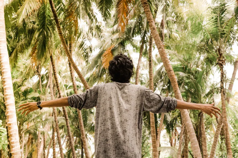 Ein Mann geht auf den Malediven zwischen Palmen spazieren