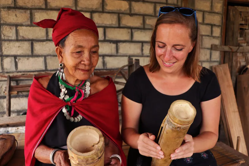 Zwei Frauen sitzen in Myanmar zusammen und schauen sich ein Musikinstrument aus Holz an