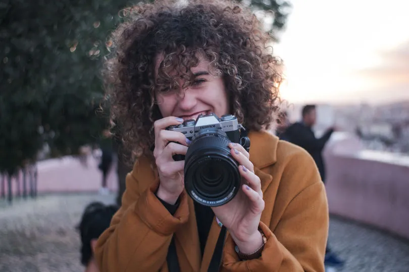 Eine Frau hält eine Kamera und lacht