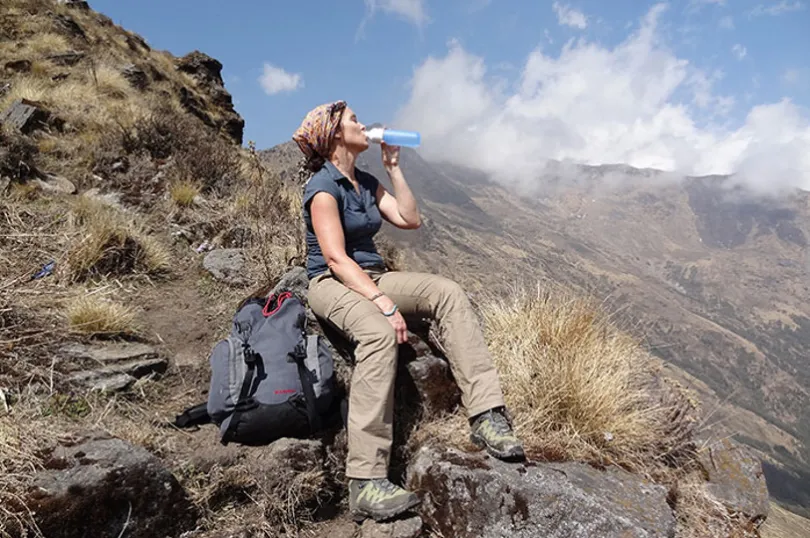 Eine Wanderin trinkt aus Ihrer Wasserflasche in Nepal