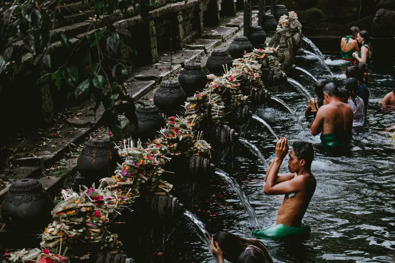 Menschen reinigen sich an einem Tempel in Indonesien