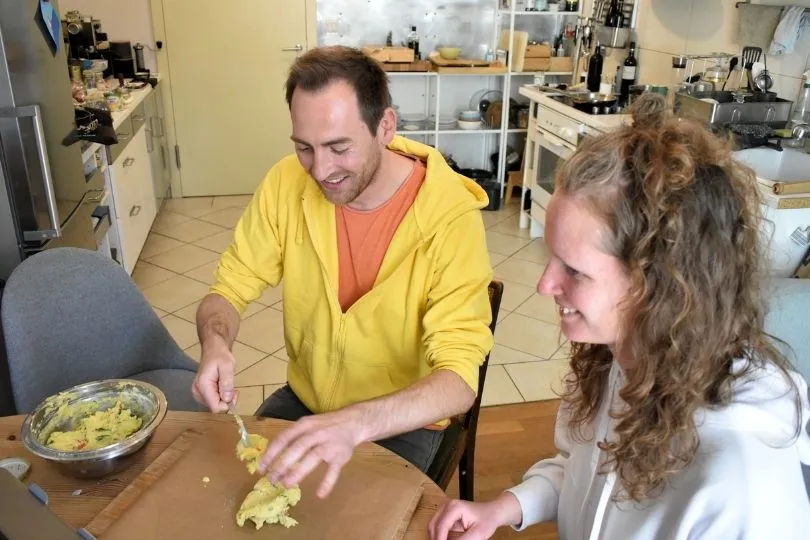 Zwei Personen sitzen am Tisch und bereiten Tamales zu