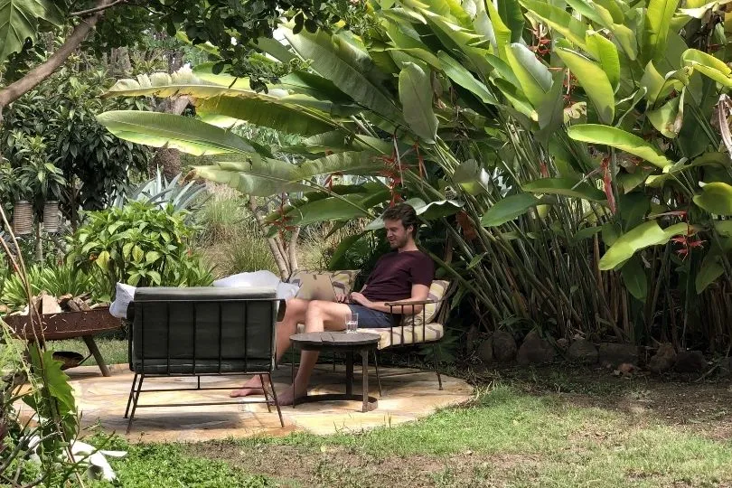 Ein Mann sitzt auf einem Liegestuhl in Tansania und arbeitet