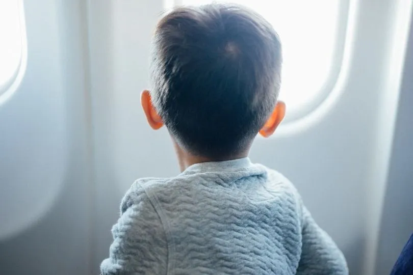 Ein Kind schaut imm Flugzeug aus dem Fenster