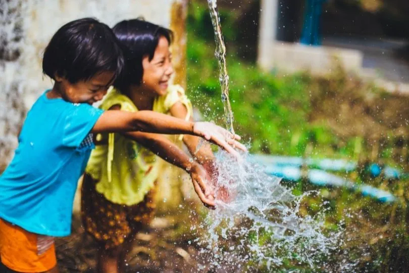 Zwei Kinder in Thailand an einem Springbrunnen