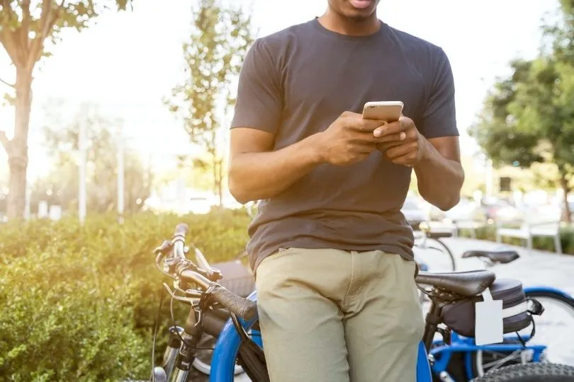 Ein Mann steht mit seinem Smartphone an einem Fahrradstände