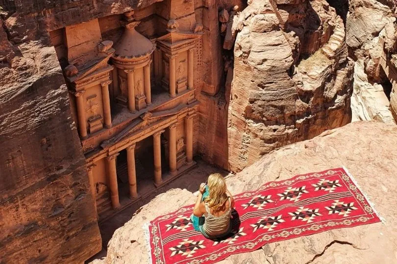 Nina sitzt auf einer Decke auf einem felsen vor Petra