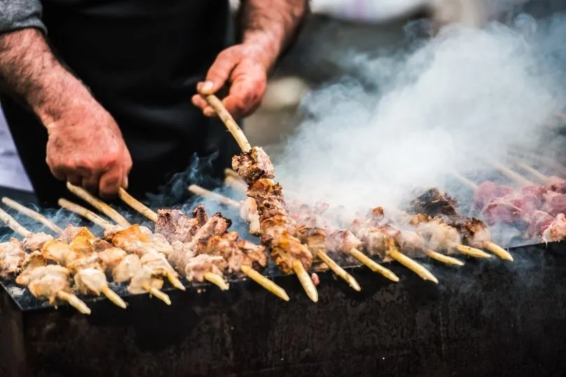 Ein Mann röstet Schaschlik Spieße in Armenien