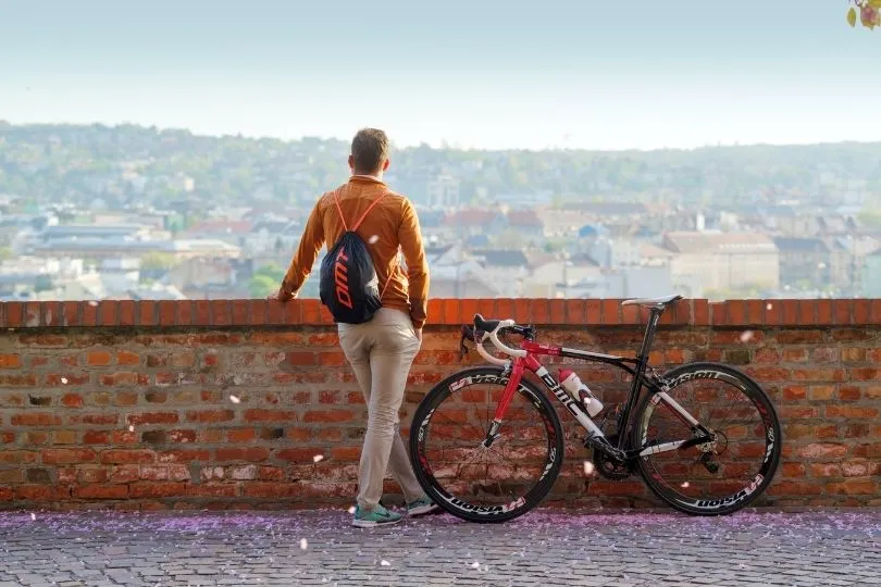 Ein Mann steht mit seinem Mountainbike an einer Mauer und schaut auf die Stadt