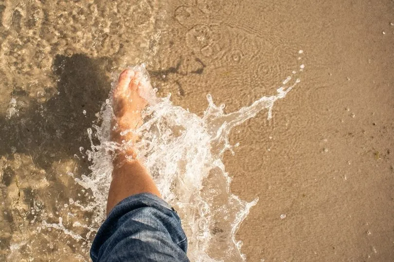 Ein Fuß im Wasser am Strand von Sardinien