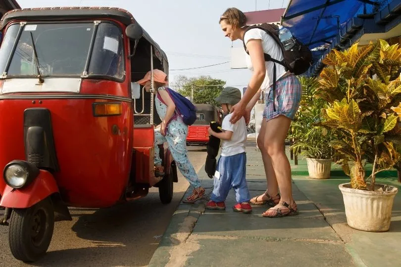 Zwei Kinder steigen mit einer Frau in ein Tuktuk in Laos ein