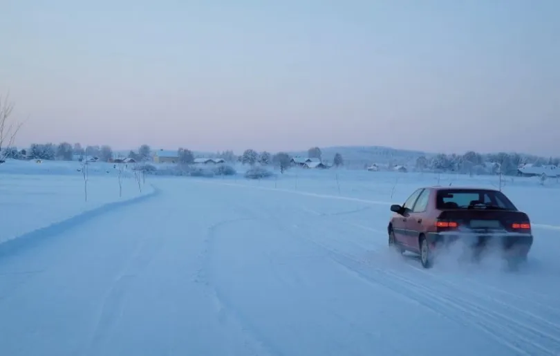 Verschneite Straße mit Auto in Schweden