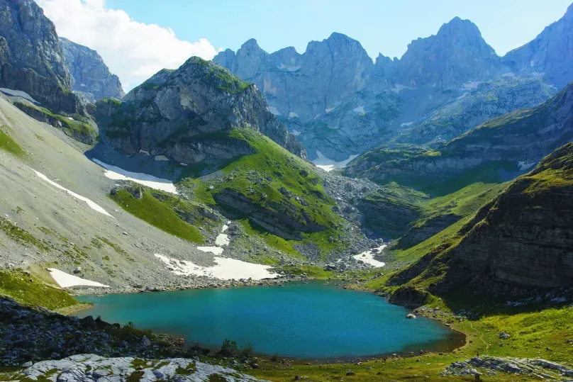 Beste Reiseziele Juni - Theth Berge rund um einen See.