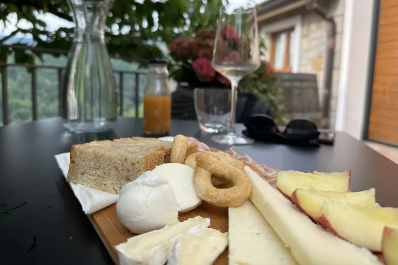 Wein, Käse und Brötchen auf dem Tisch.