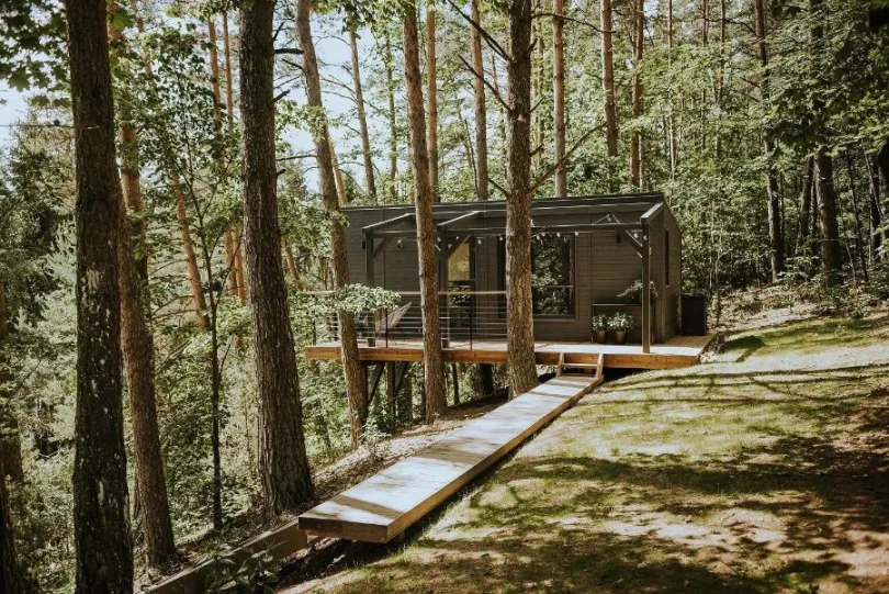 Eine Holzhütte im Wald mit Sonnenschein, Lettland.