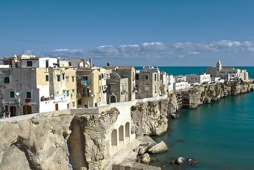 Küstenstadt Gargano mit weißen Gebäuden auf einer felsigen Klippe, mit blaues Meer blicken.