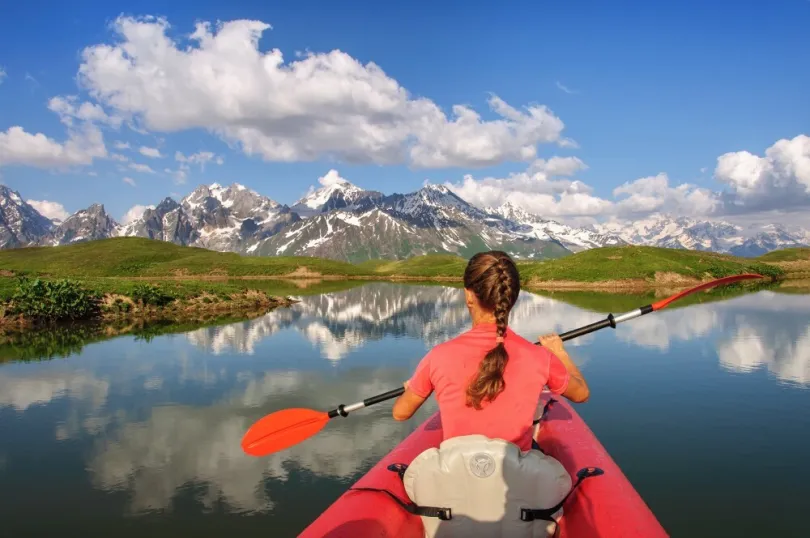 Georgien - Lake Koruldi_Ein Mädchen auf einem roten Kanu mit wunderschönem Blick auf die Berge