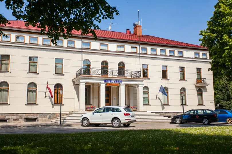 Großes Hotel mit Auto draußen parken.