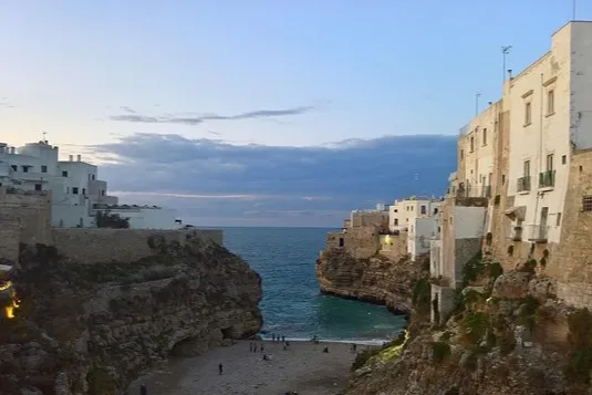 Küstenstadt Polignano bei Sonnenuntergang mit Strand.
