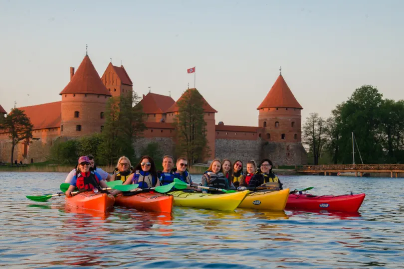 Eine Reisegruppe auf einer Kayak Tour auf dem See mit einem Schloss im Hintergrund.