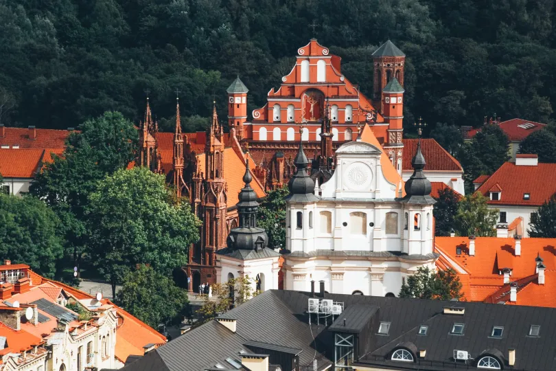 Aussicht auf einer weißen Kirche neben einem dunklen orangen Hochhaus in Vilnius, Lettland.