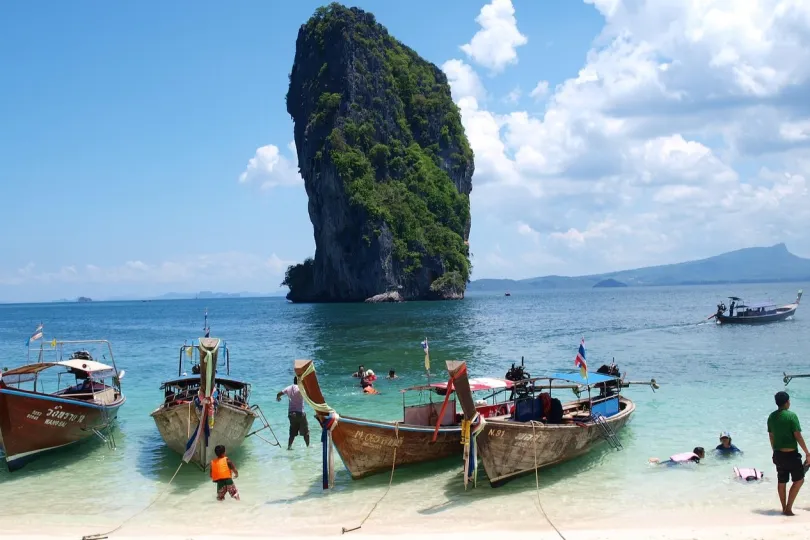 Boote am Strank vor Kalksteinfelsen in Thailand.