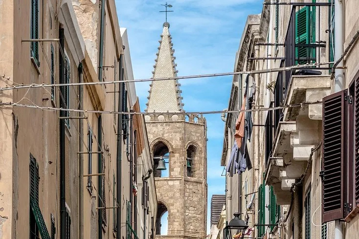 Enge Gasse, die von alten Gebäuden gesäumt ist. Im Hintergrund ist das Algehro Kirchturm.