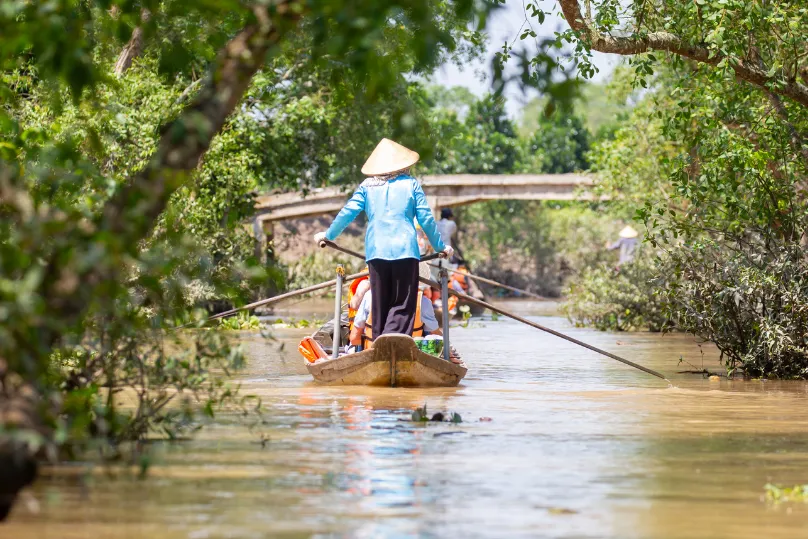 Leute auf einem Holzboot auf einem Fluss der Mekong Delta, Vietnam.