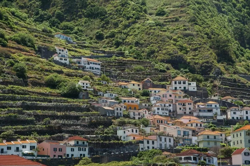 Hügel mit terrasierten Feldern und bunten Häusern in Porto Moniz.