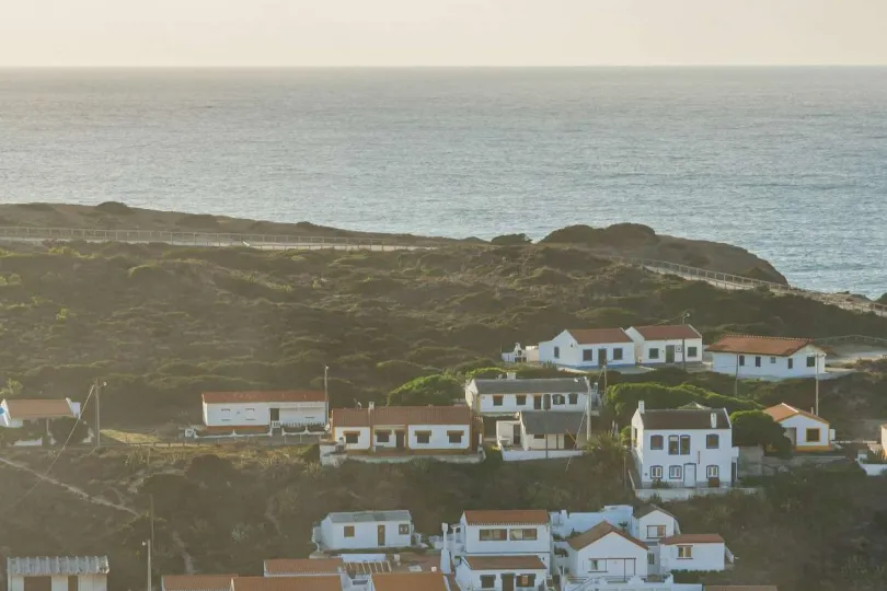 Ein Küstendorf mit weißen Häusern und roten Ziegeldächern, das auf einem Hügel mit Blick auf das Meer liegt.