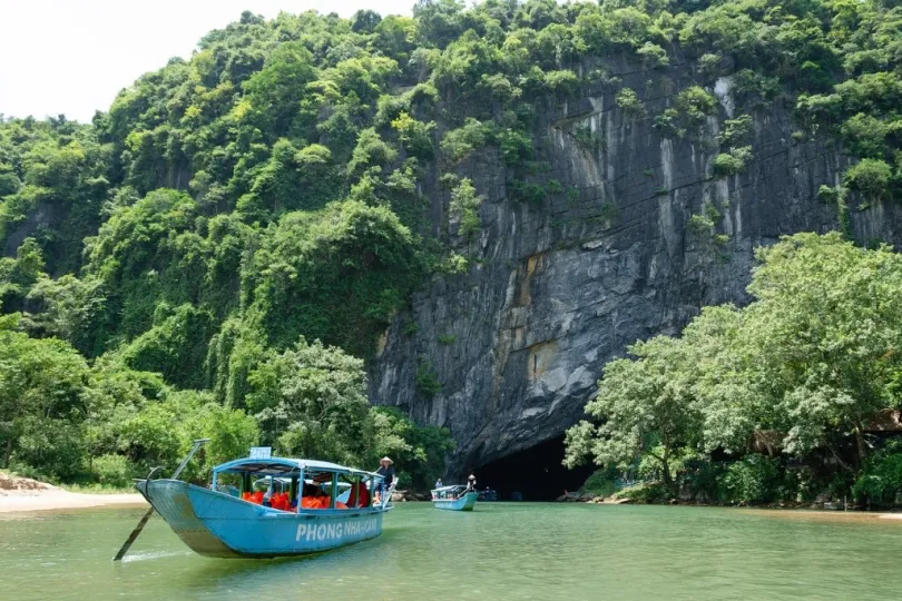 Boote auf einem Fluss, umgeben von üppigen grünen Bäumen und Vegetation.