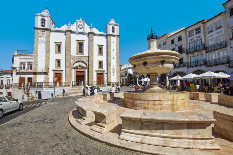kunstvollen Brunnen im Vordergrund und einer prächtigen Kirche mit zwei Glockentürmen im Hintergrund.