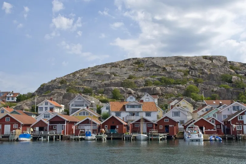Küstendorf mit rot-weißen Häusern auf Stelzen am Wasser.