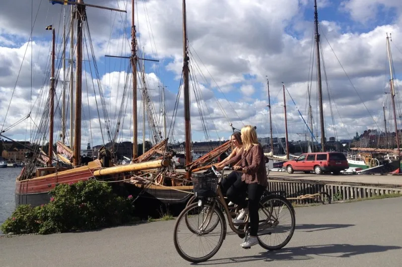  zwei Personen, die auf einem gepflasterten Weg in der Nähe eines Hafens Fahrrad fahren. 