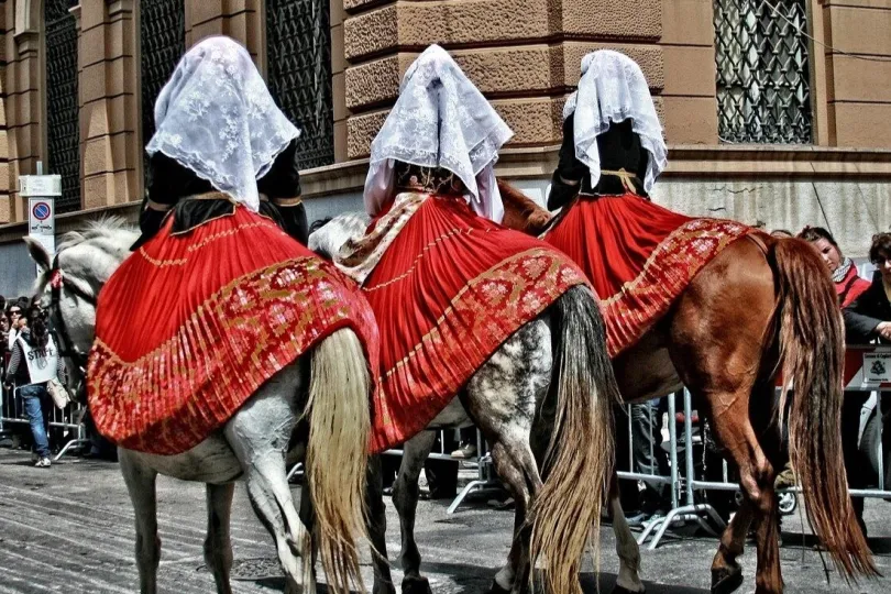drei Personen, die in einer Parade oder Prozession auf Pferden reiten.