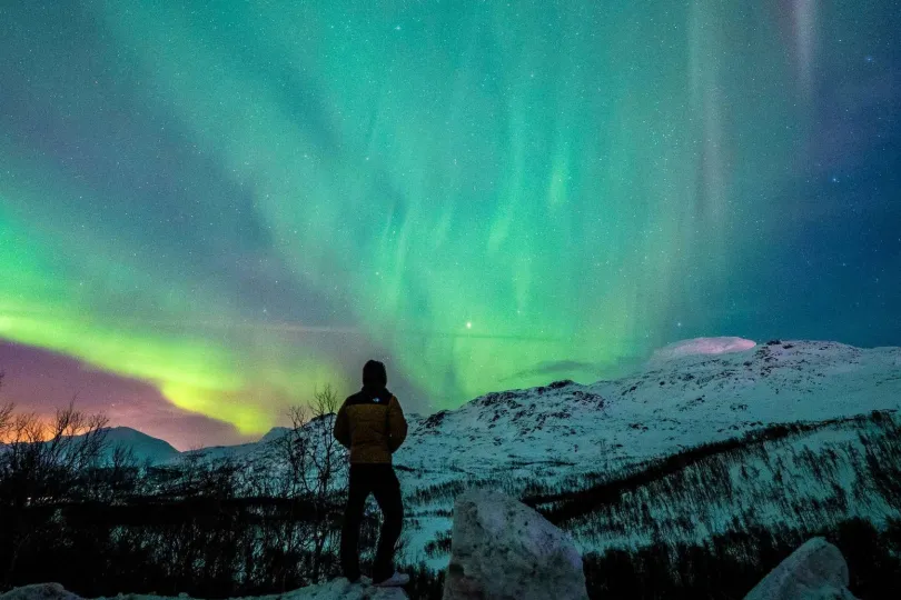 Ein Person steht vor die Nordlichter in Norwegen.
