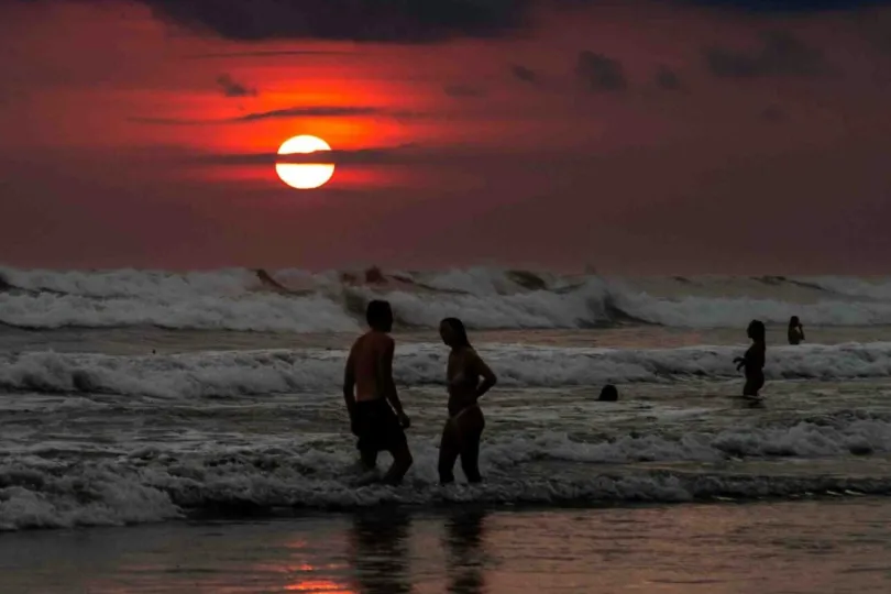 Menschen am Strand beim Sonnenuntergang.