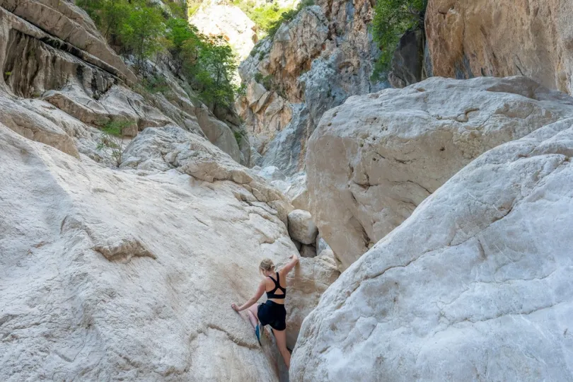 Ein Person die über große Felsen in Goroppu Canyon klettert.