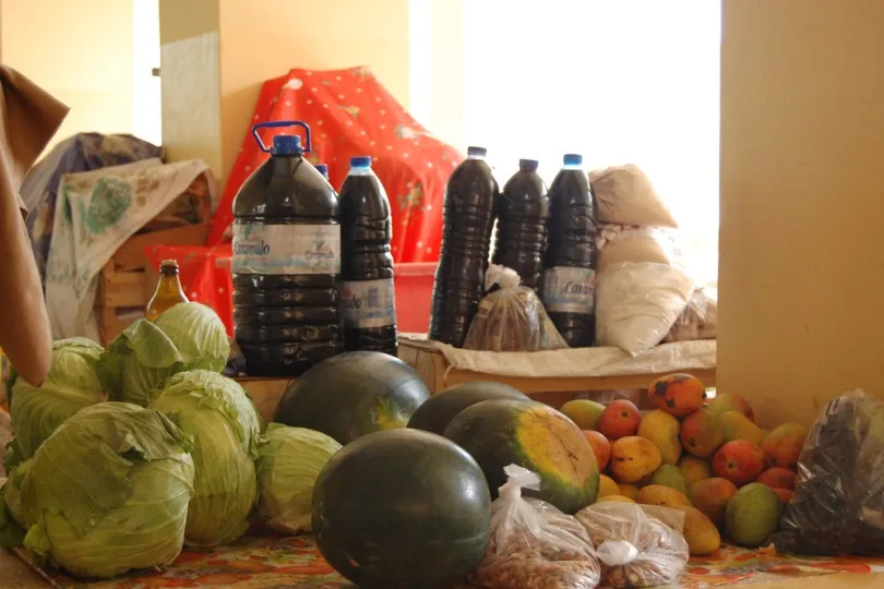 Marktstand mit Flaschen, Körnern, Kohl, Wassermelonen, Mango.