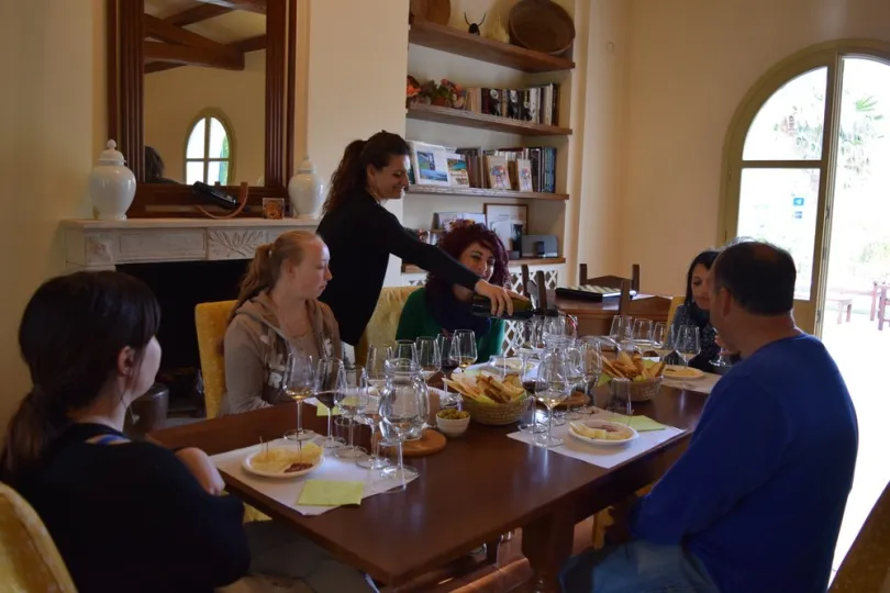eine Gruppe von Menschen beim Essen an einem schön gedeckten Tisch. Eine Person schenkt Wein ein.