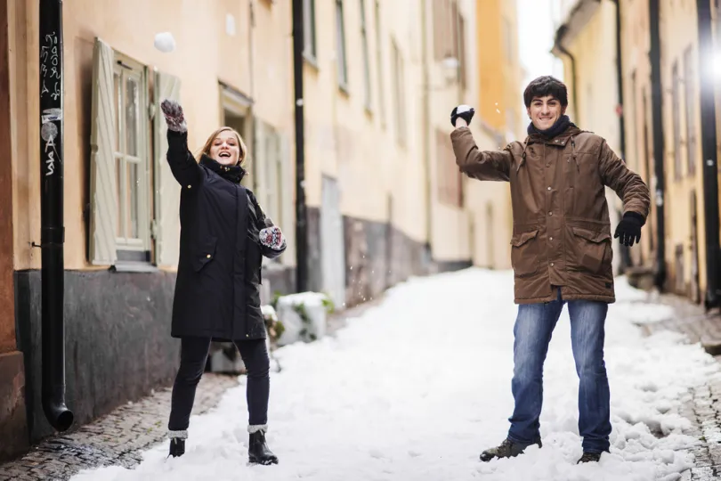 Zwei Personen spielen mit schnee.